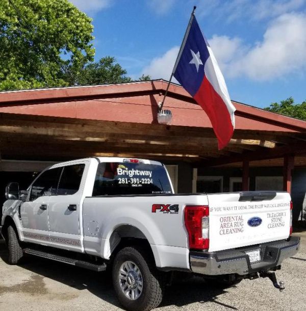 A white truck parked in front of a building with a texas flag.